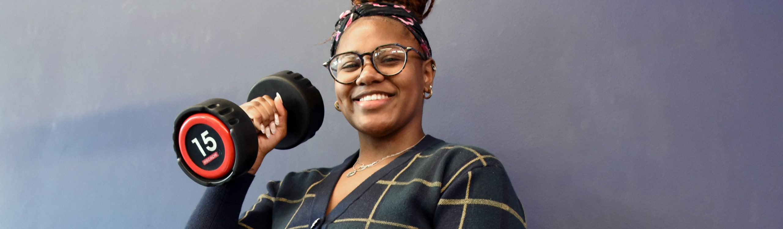 Woman smiling while holding a dumbbell weight