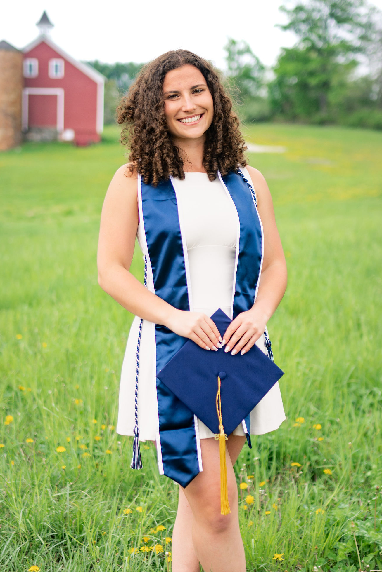 Kaitlyn Parri in a green field in font of uconn's red barn